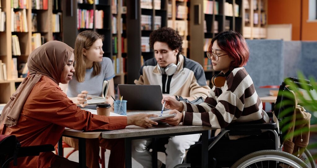 Group of diverse male and female students spending time together studying in library